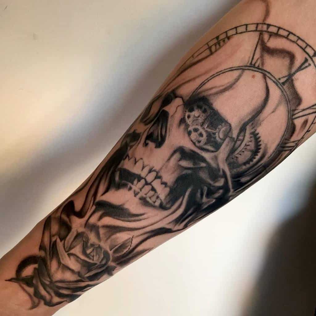 A black and grey forearm tattoo featuring a detailed skull entwined with smoke, mechanical gears, and a clock, blending steampunk elements with dark, realistic shading