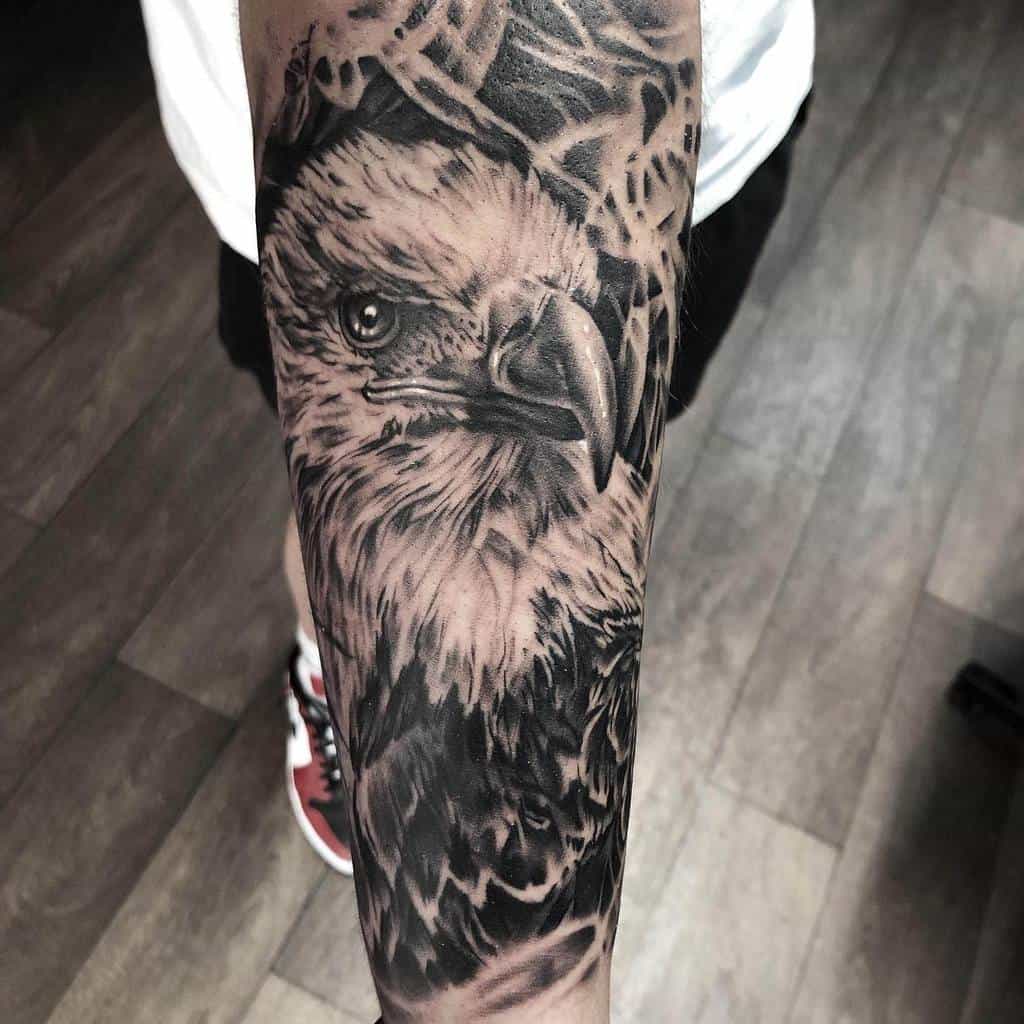 A realistic eagle head tattoo with intricate shading on the forearm, creating a bold and lifelike statement piece