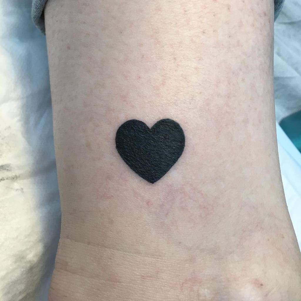 Simple yet impactful solid black heart tattoo, symbolizing clarity and love in a minimalist design