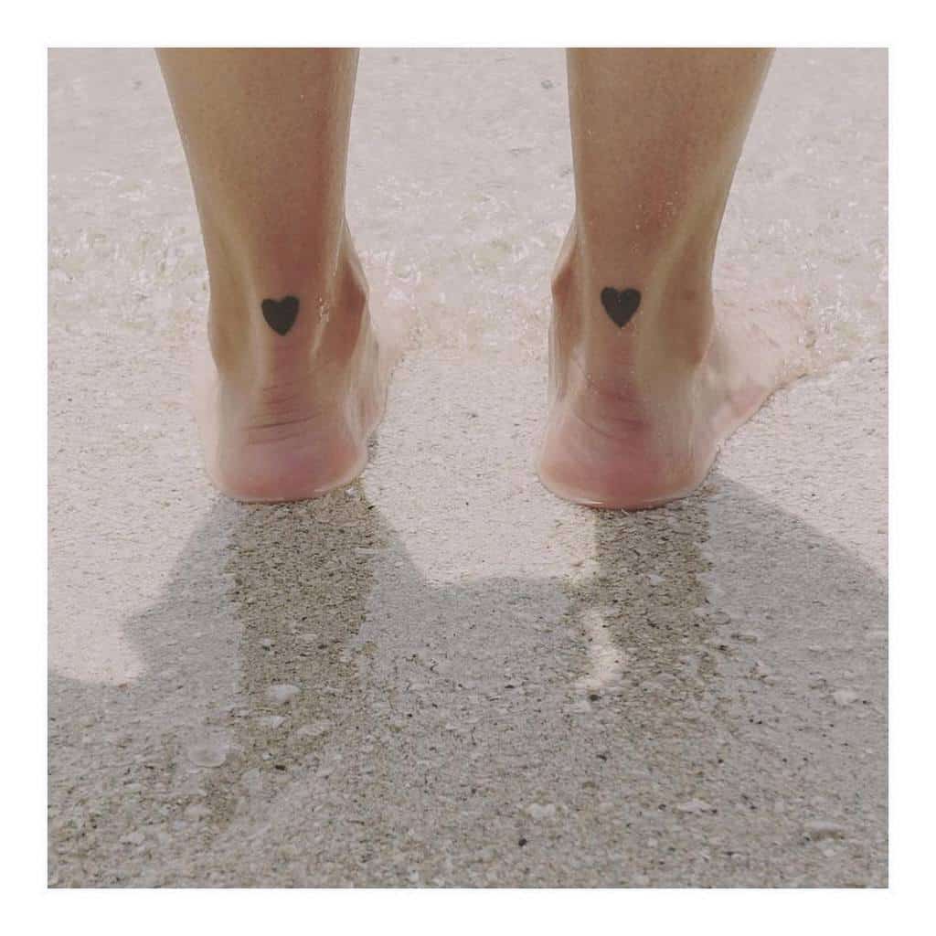 Matching two small black solid heart tattoos