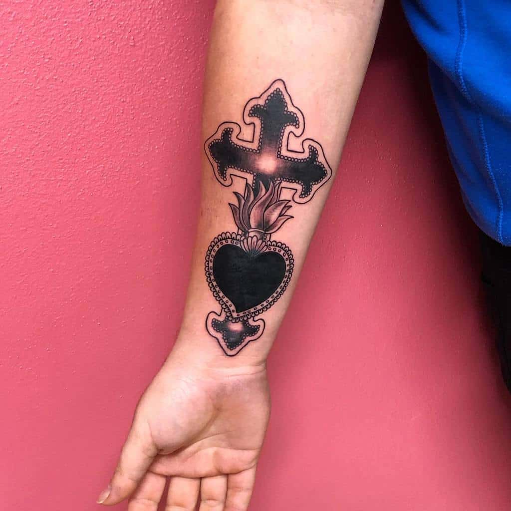 Bold black sacred heart tattoo with intricate beaded detailing, a flaming crown top, and a gothic cross