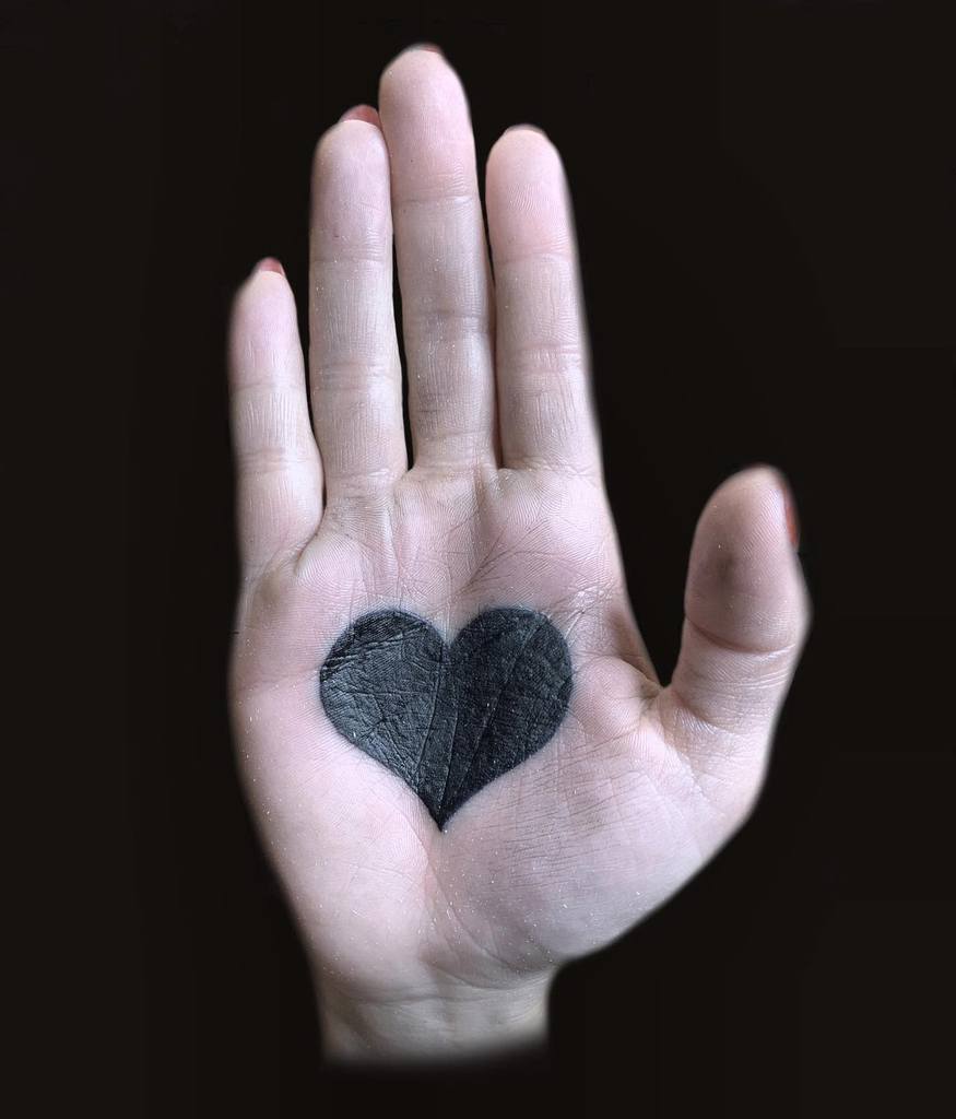 Bold black heart tattoo, creating a striking and unconventional design with deep symbolic meaning