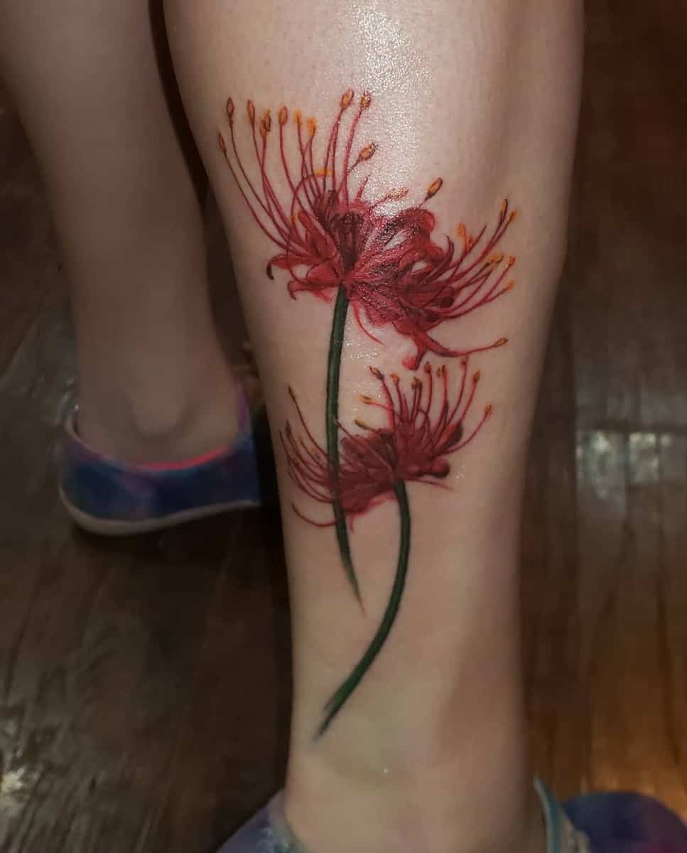 Leg tattoo of two red spider lilies, often symbolizing death and rebirth, with delicate shading and vibrant colors.
