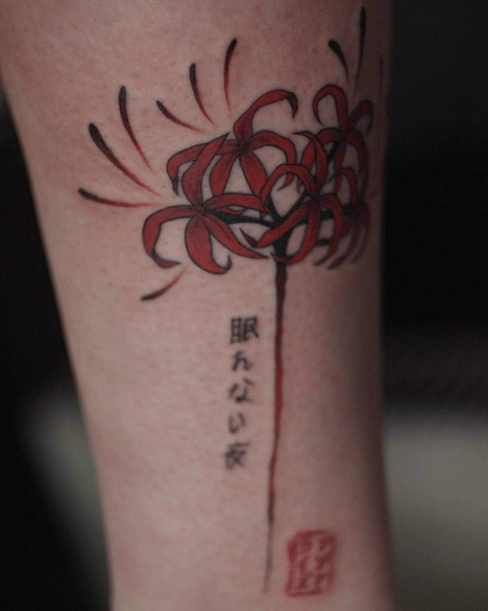 A tattoo of red spider lilies with Japanese text, symbolizing death and rebirth