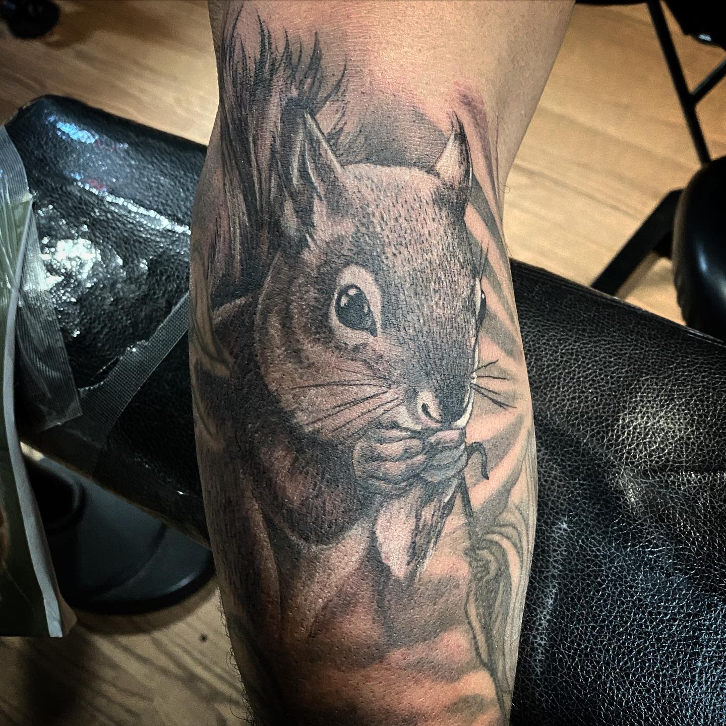 Tattoo of a realistic squirrel holding food on a forearm
