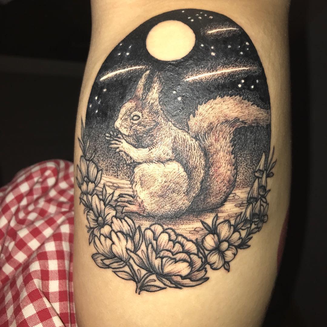 Squirrel tattoo under a full moon, surrounded by flowers, on an arm