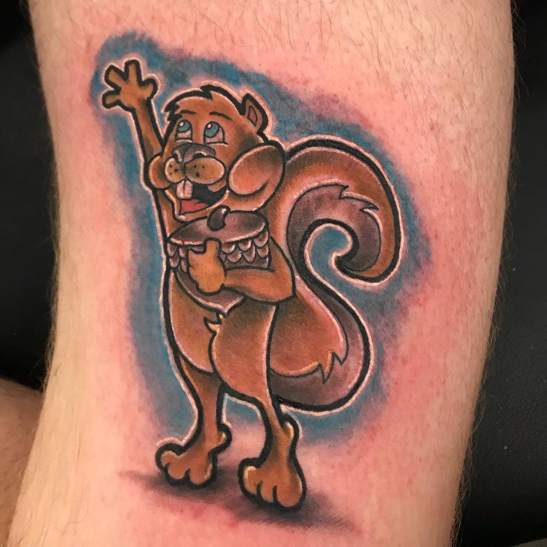 Tattoo of a cute cartoon squirrel holding an acorn with one hand raised in the air