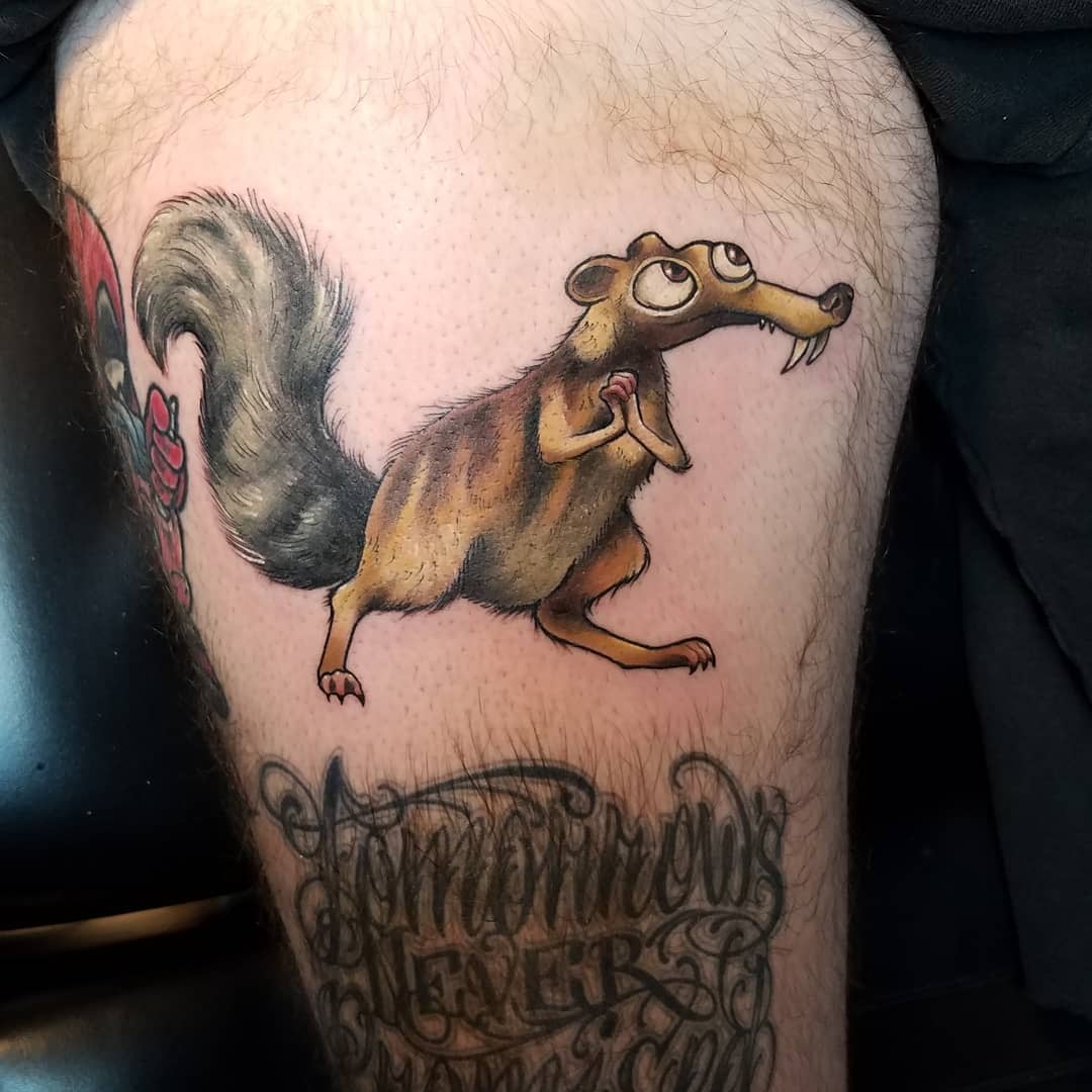 Tattoo of an animated squirrel-like character holding an acorn on an upper leg