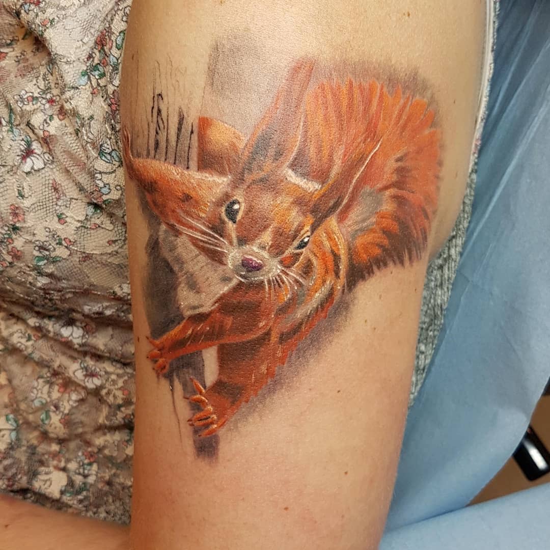 Realistic squirrel tattoo on an upper arm, showing detailed fur and vibrant colors