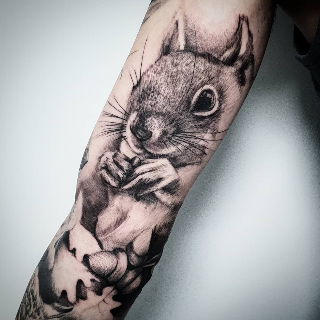 Black and white tattoo of a detailed squirrel covering the length of a forearm