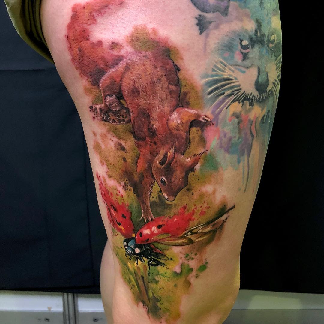 Colorful tattoo of a squirrel and a ladybug on an upper leg with abstract elements
