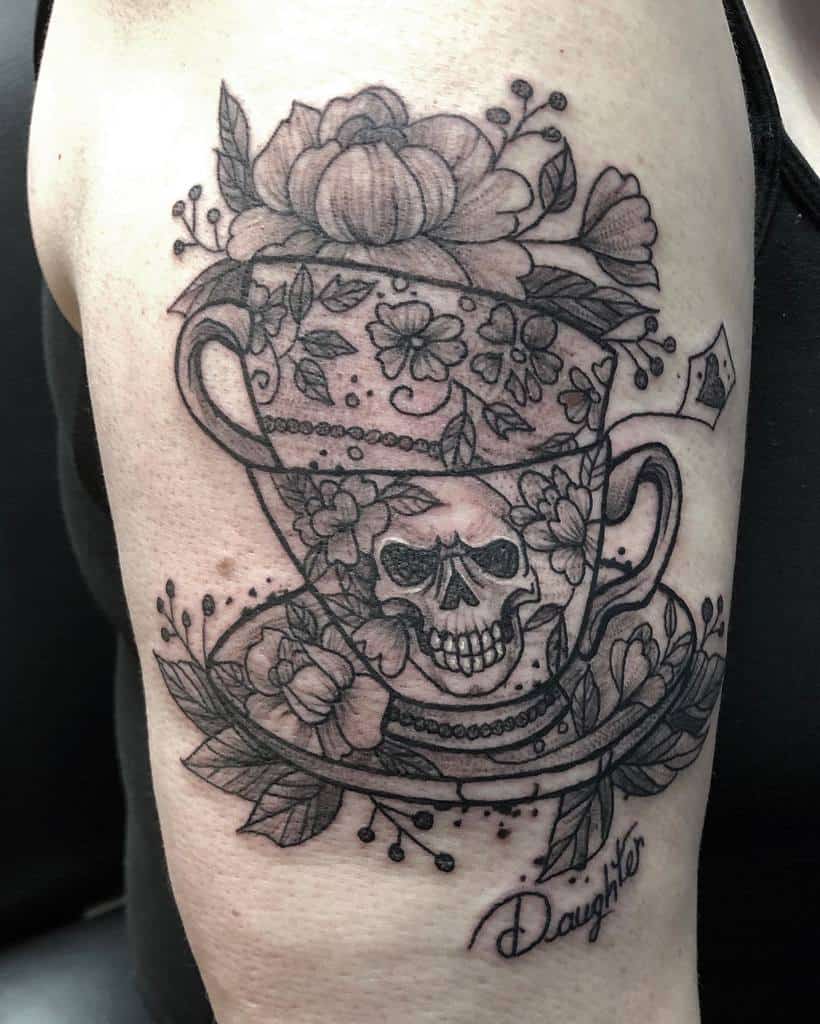 Black and grey tattoo of stacked floral teacups, with a skull on one cup, surrounded by flowers and leaves, and the word "Daughter"