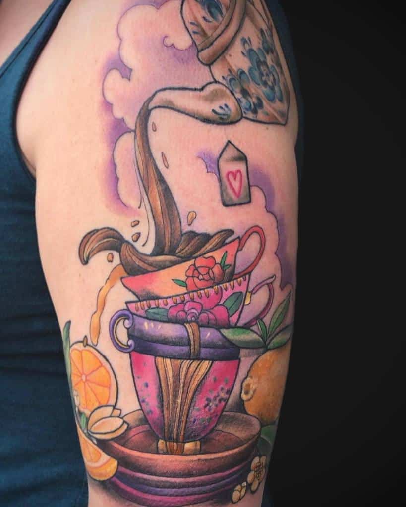 Detailed tattoo of a vintage teapot pouring tea into stacked floral teacups, with steam, a teabag, oranges, leaves, and blossoms