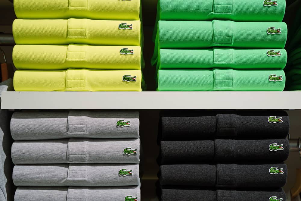 Stacks of Lacoste polos in various colors lined up on a shelf