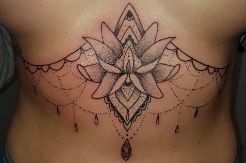 Elegant chandelier tattoo with a large lotus flower, intricate dot work, ornamental details, and cascading beaded chains with gemstone pendant