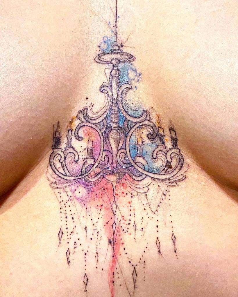 Ornate chandelier tattoo with delicate six candle details, watercolor splashes of blue, pink and violet, and elegant dangling crystal accents with intricate dot work