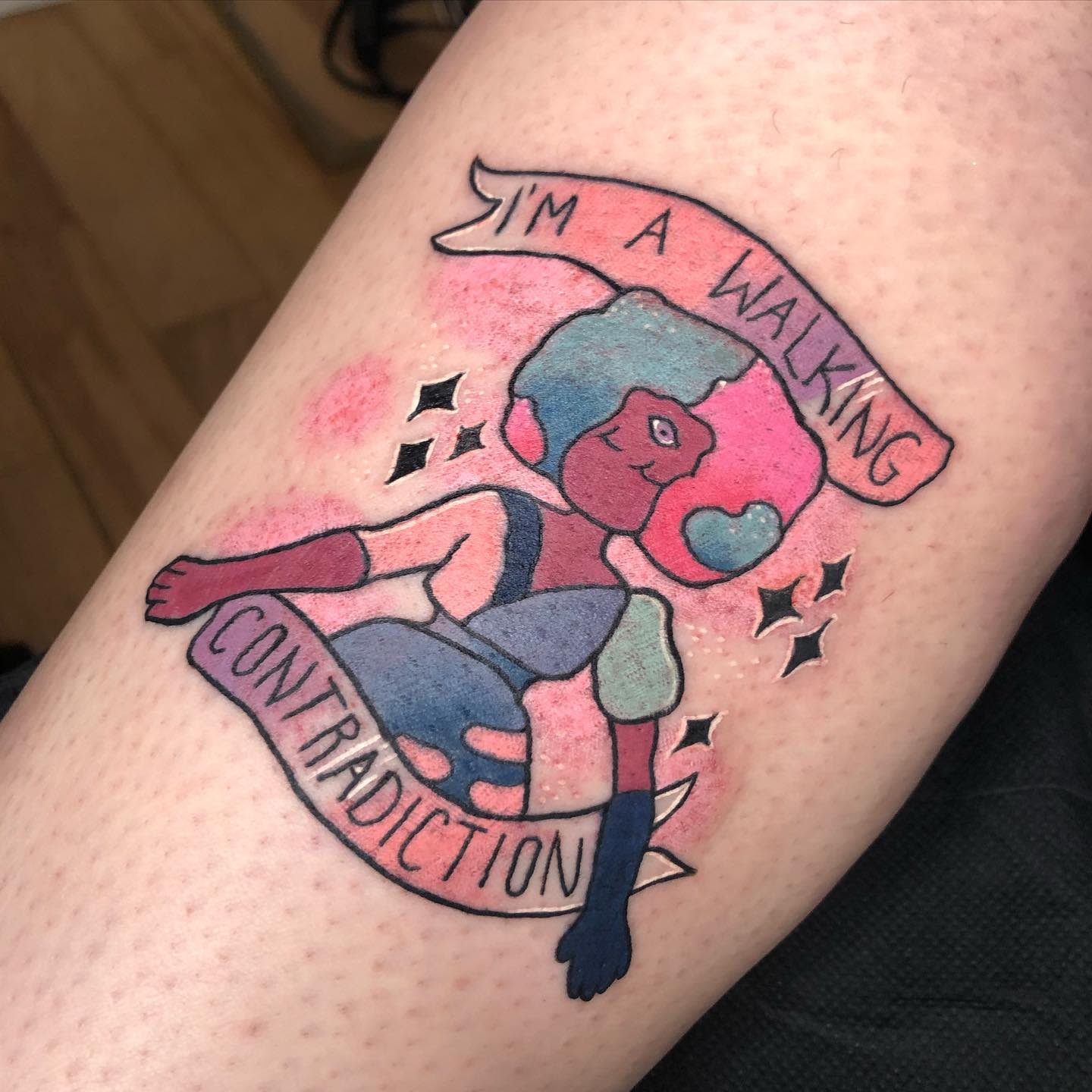 A colorful Garnet tattoo from Steven Universe with a banner that reads 'I'm a walking contradiction,' featuring bright hues and small sparkles, emphasizing the character's duality