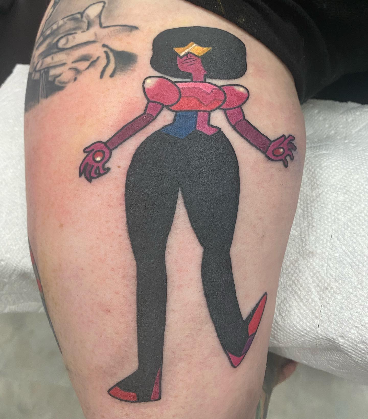 Colorful tattoo of Garnet from Steven Universe in a full-body pose, featuring her signature visor and confident stance, on the upper thigh