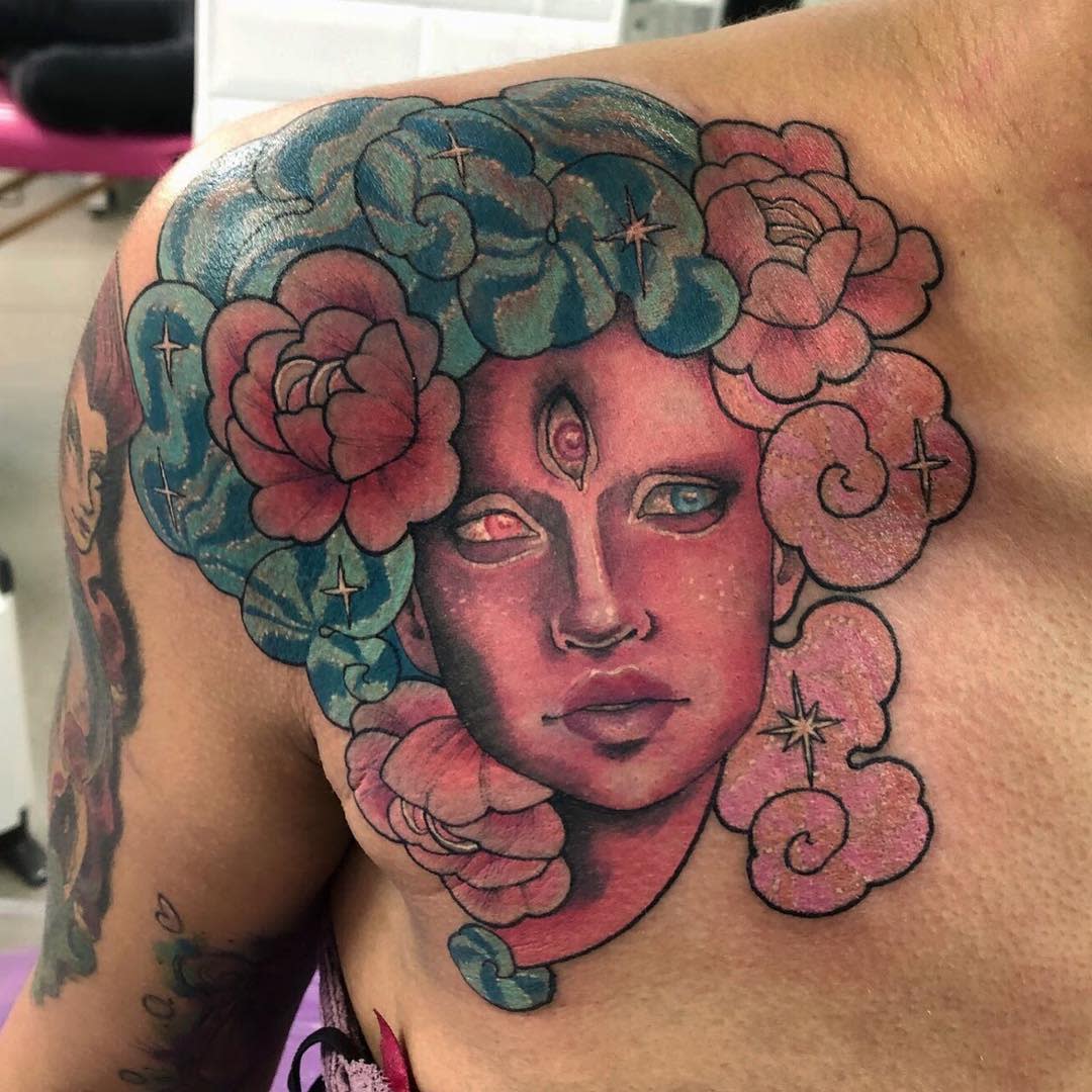 Colorful and detailed chest tattoo of Garnet from Steven Universe, featuring her three-eyed face surrounded by vibrant flowers and swirling patterns in her hair