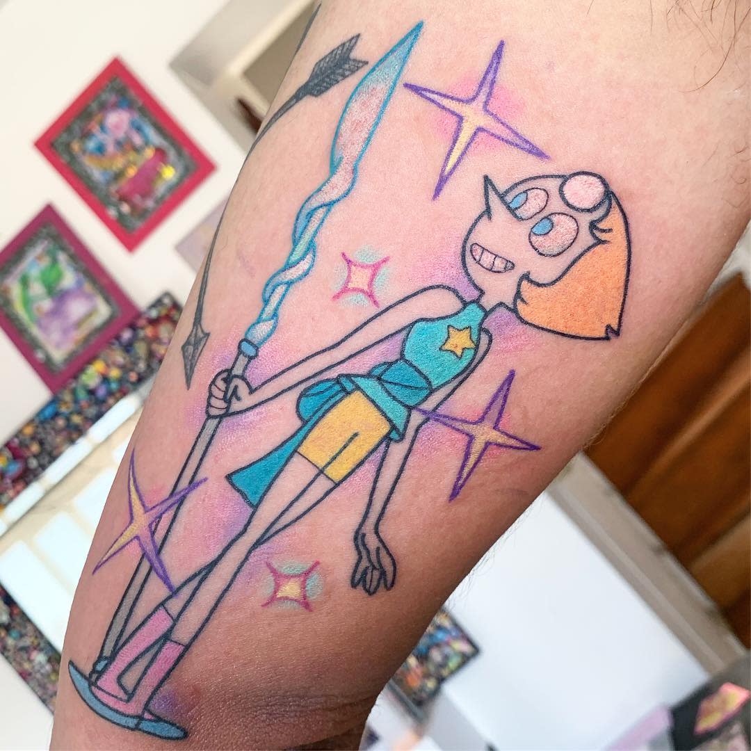Vibrant tattoo of Pearl from Steven Universe, smiling and holding her spear, surrounded by sparkling stars, on the arm