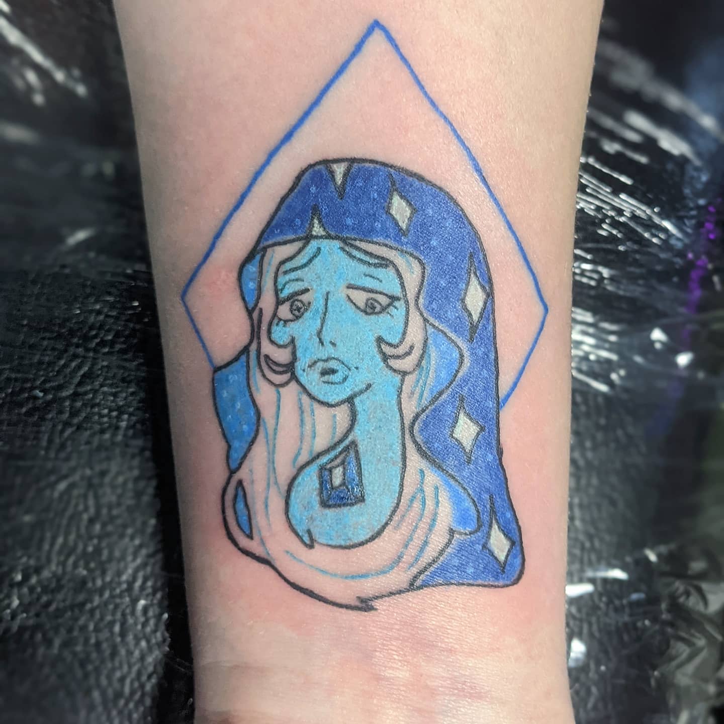 Blue Diamond tattoo from Steven Universe, with a tearful expression, framed by a blue diamond outline