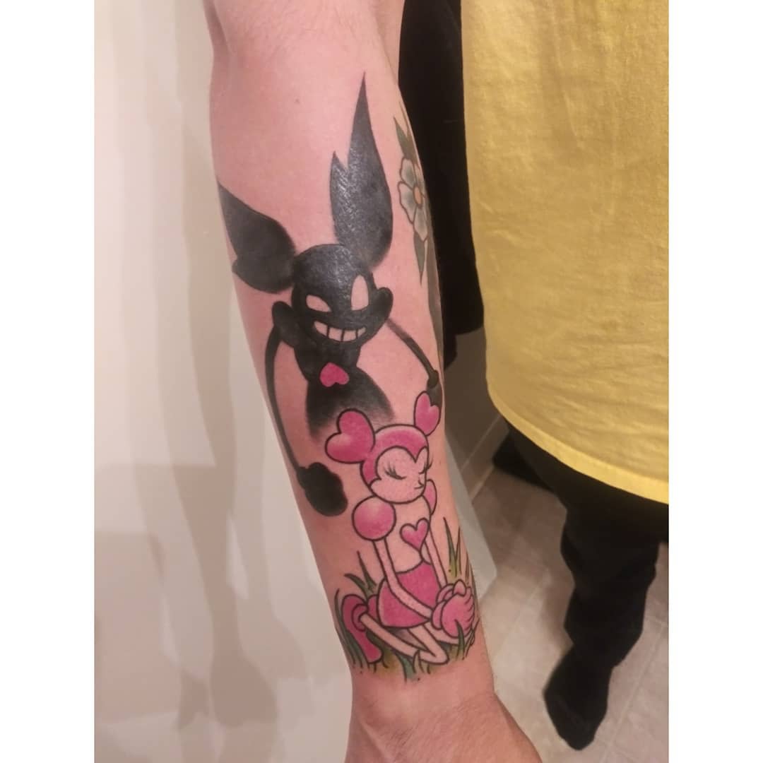 Stylized tattoo of Spinel from Steven Universe, featuring her with a mischievous expression, holding a heart-shaped object while a shadowy figure looms over her, on the forearm