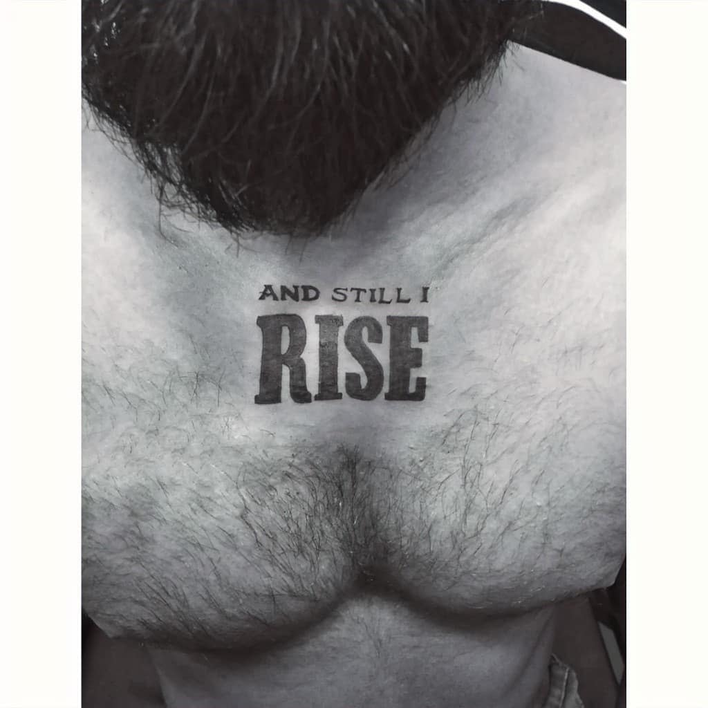 A chest with a tattoo that reads "AND STILL I RISE" in bold black letters