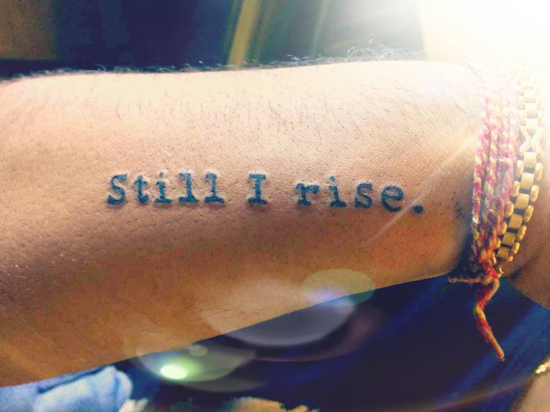 Tattoo on an arm reading "Still I rise" 