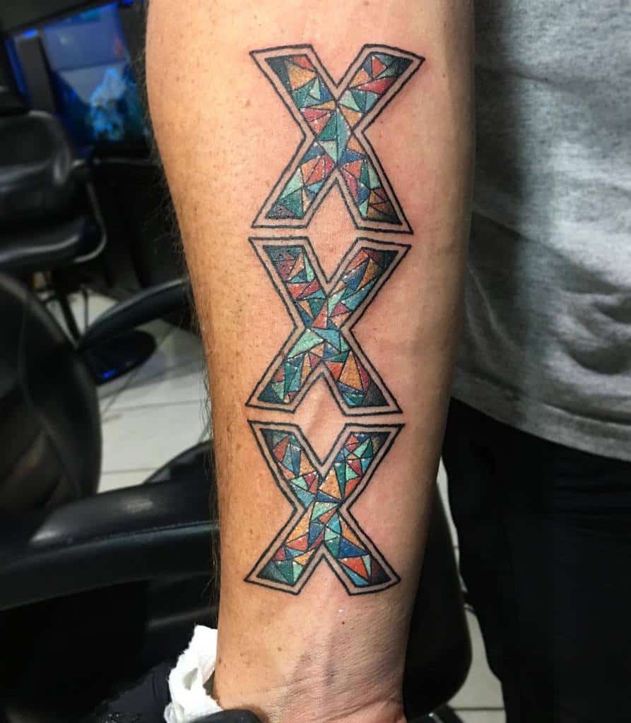 Intricate 'XXX' straight edge tattoo with a geometric stained-glass pattern
