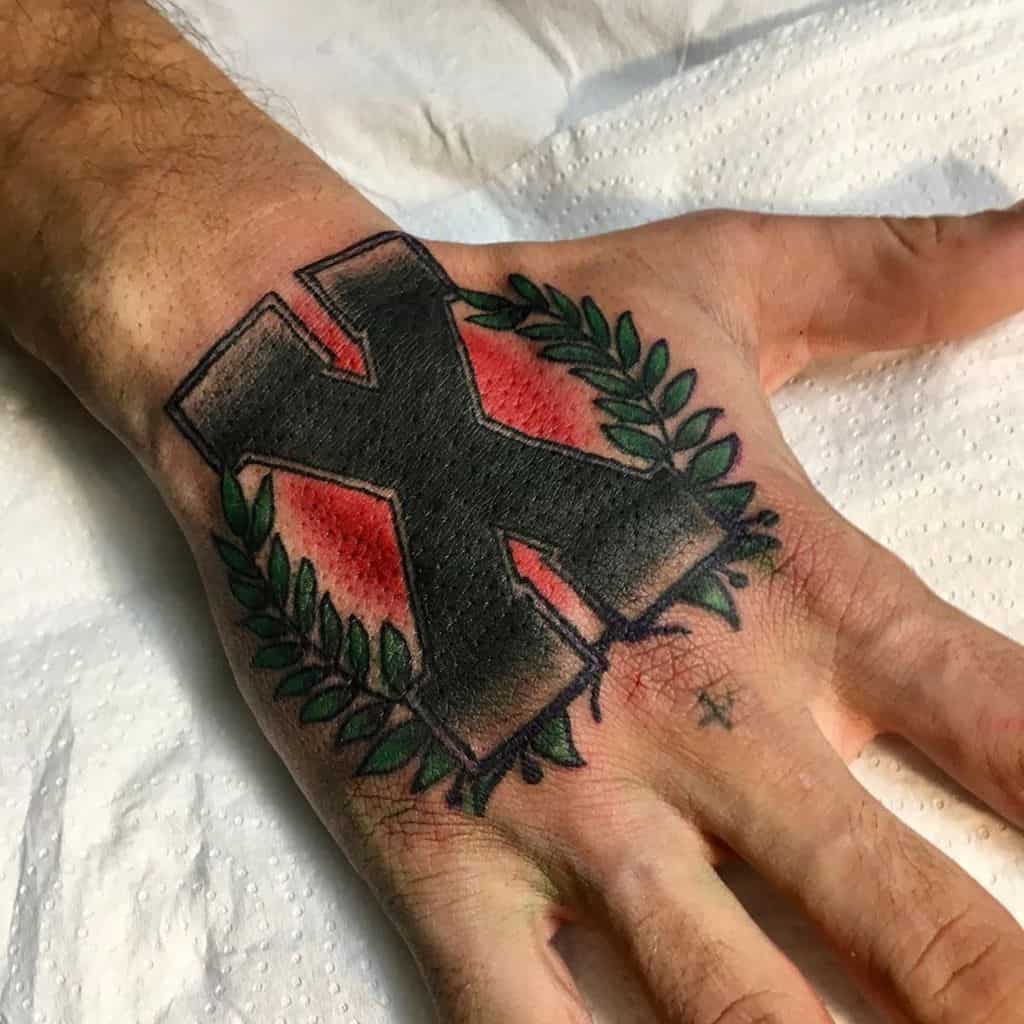 Bold hand tattoo featuring a large black Straight Edge 'X' framed by green laurel leaves and red shading