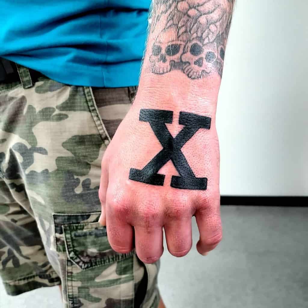 Close-up of a hand with a large black "X" straight edge tattooed on it