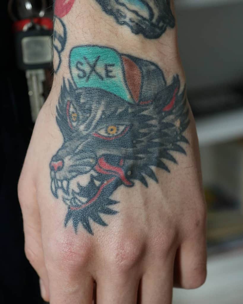 Hand tattoo featuring a fierce black wolf wearing a cap with 'SXE' written on it, symbolizing straight edge lifestyle