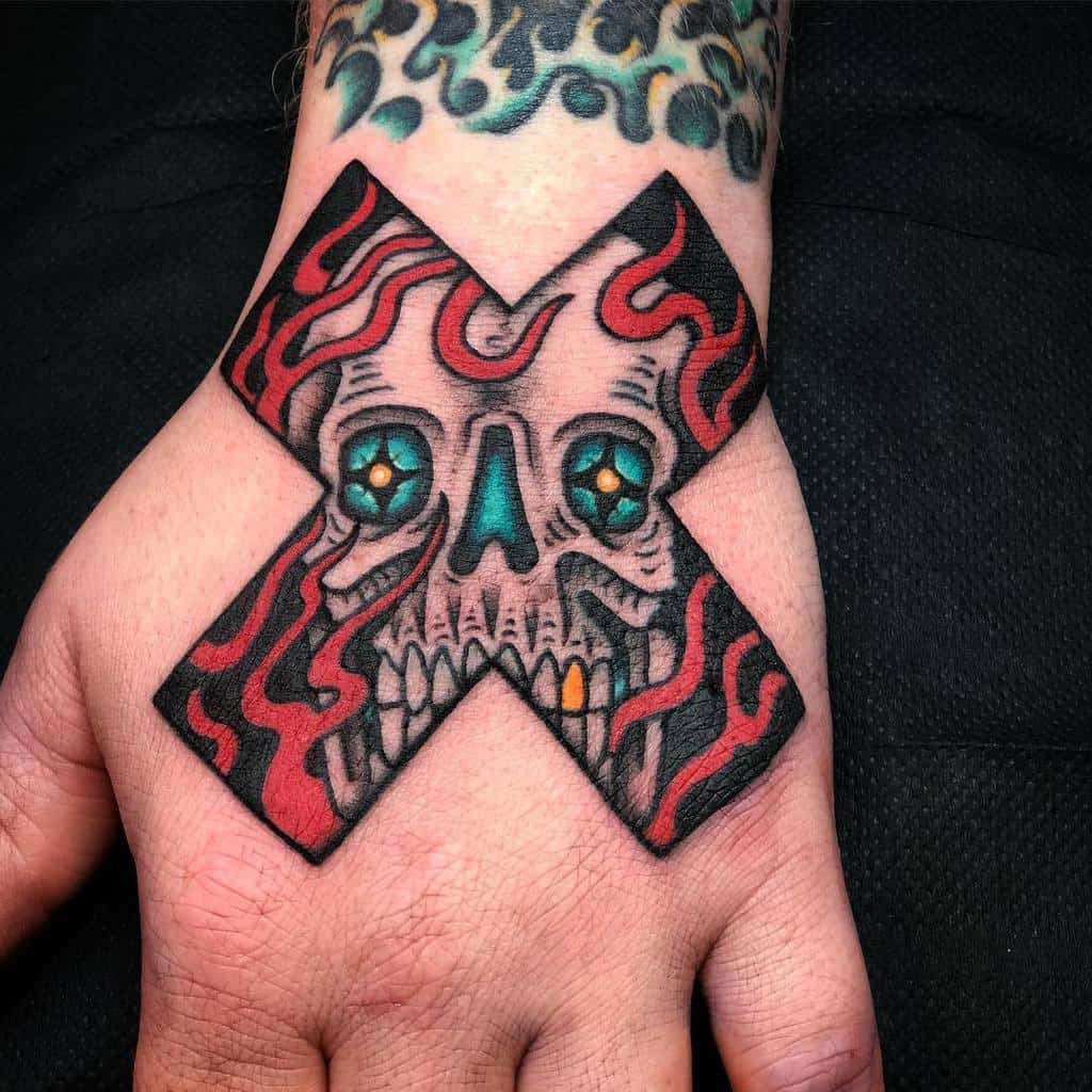 Bold hand tattoo featuring a fiery black and red straight edge 'X' with a skull at its center, glowing teal eyes, and intricate shading