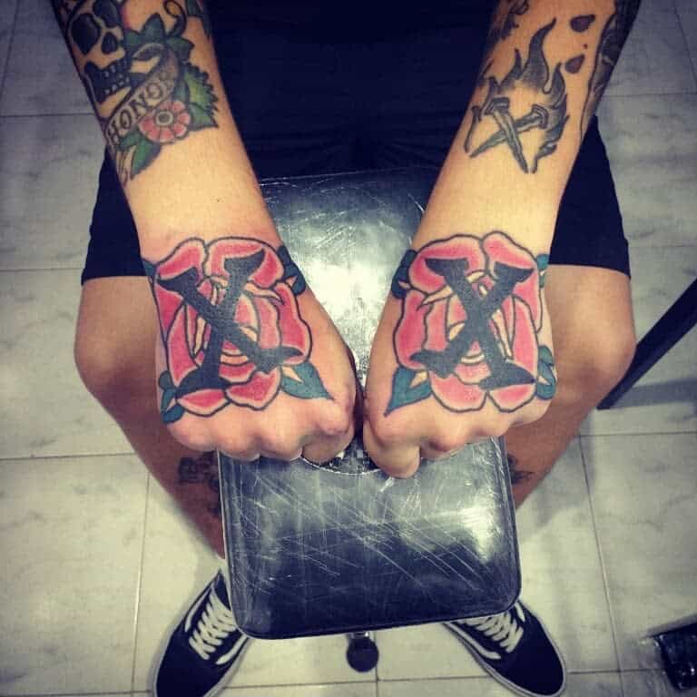 Bold hand tattoos featuring black straight edge 'X' symbols over red roses