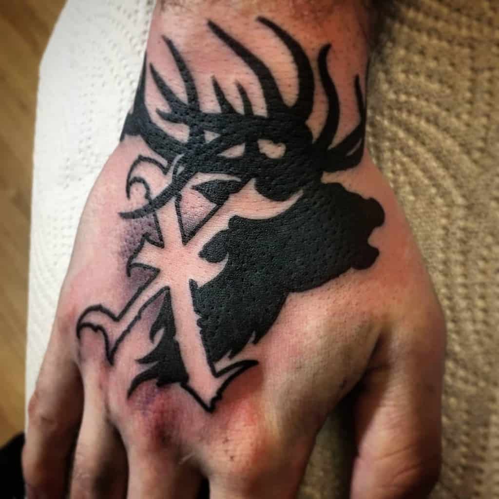 Bold black hand tattoo featuring a detailed stag silhouette with an ornate straight edge 'X'