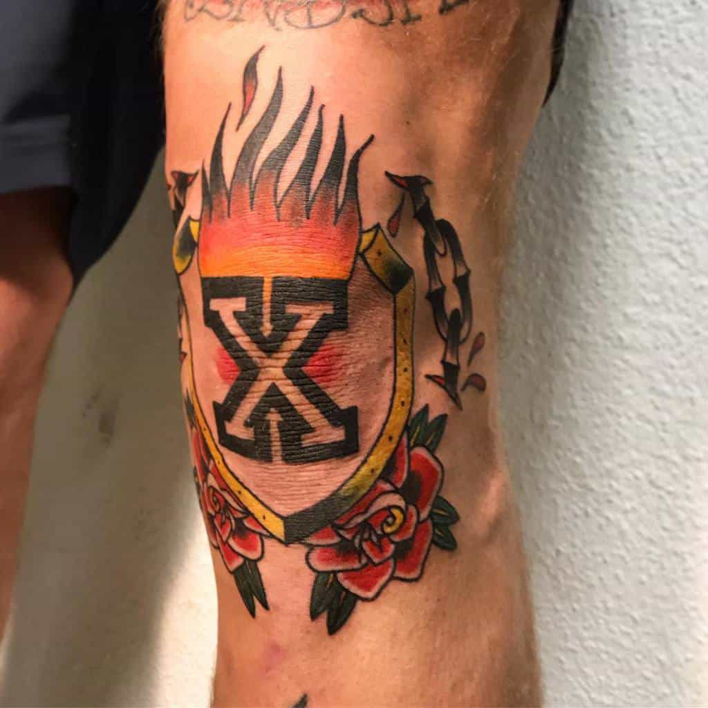 Straight edge tattoo featuring a bold black 'X' inside a flaming gold shield with black chain with red droplets, red roses and green leaves