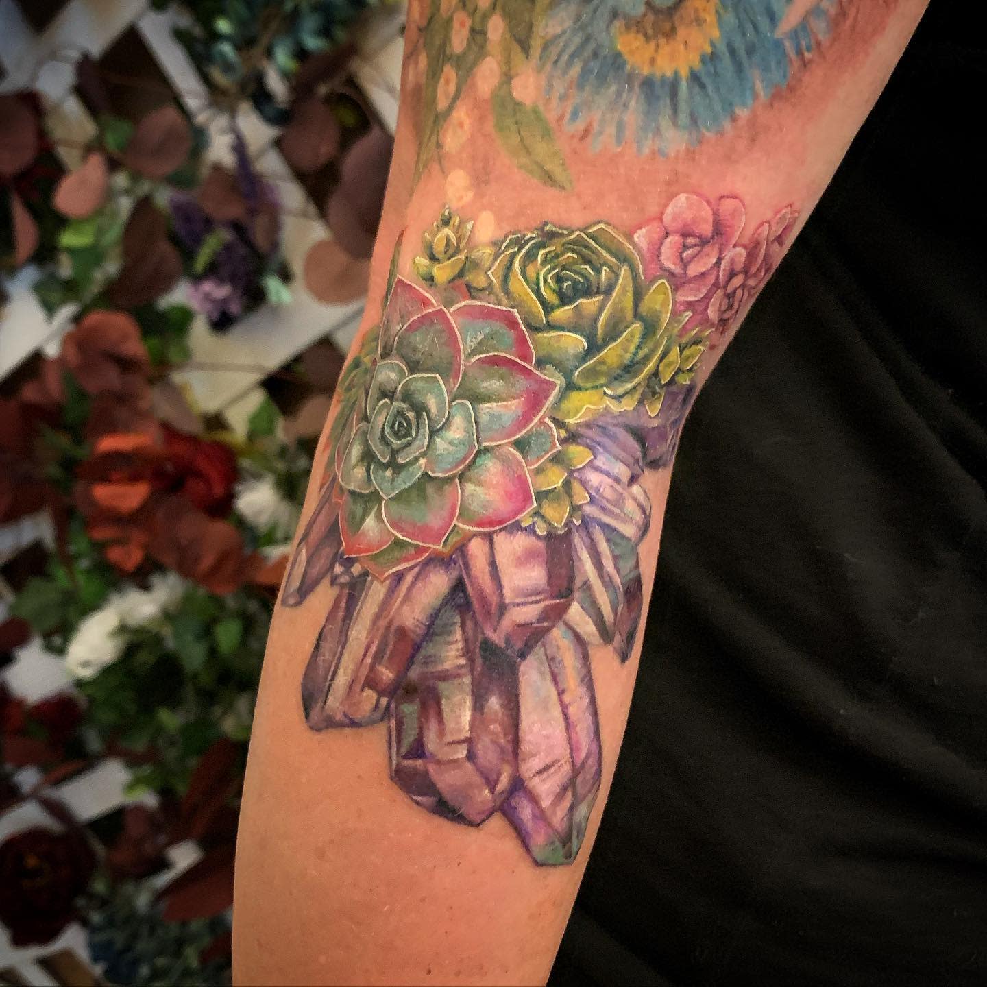 Tattoo of succulents and purple crystals on a forearm