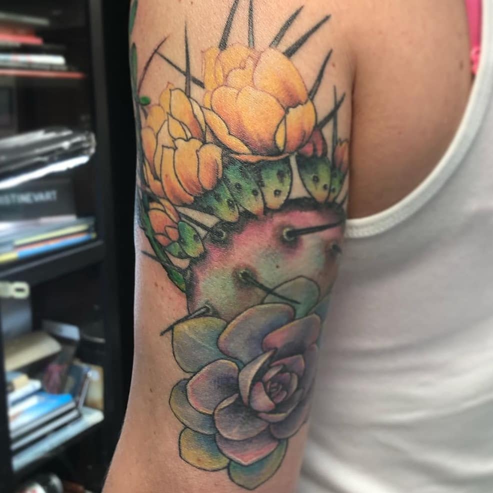 A colorful cactus and succulent tattoo on an upper arm