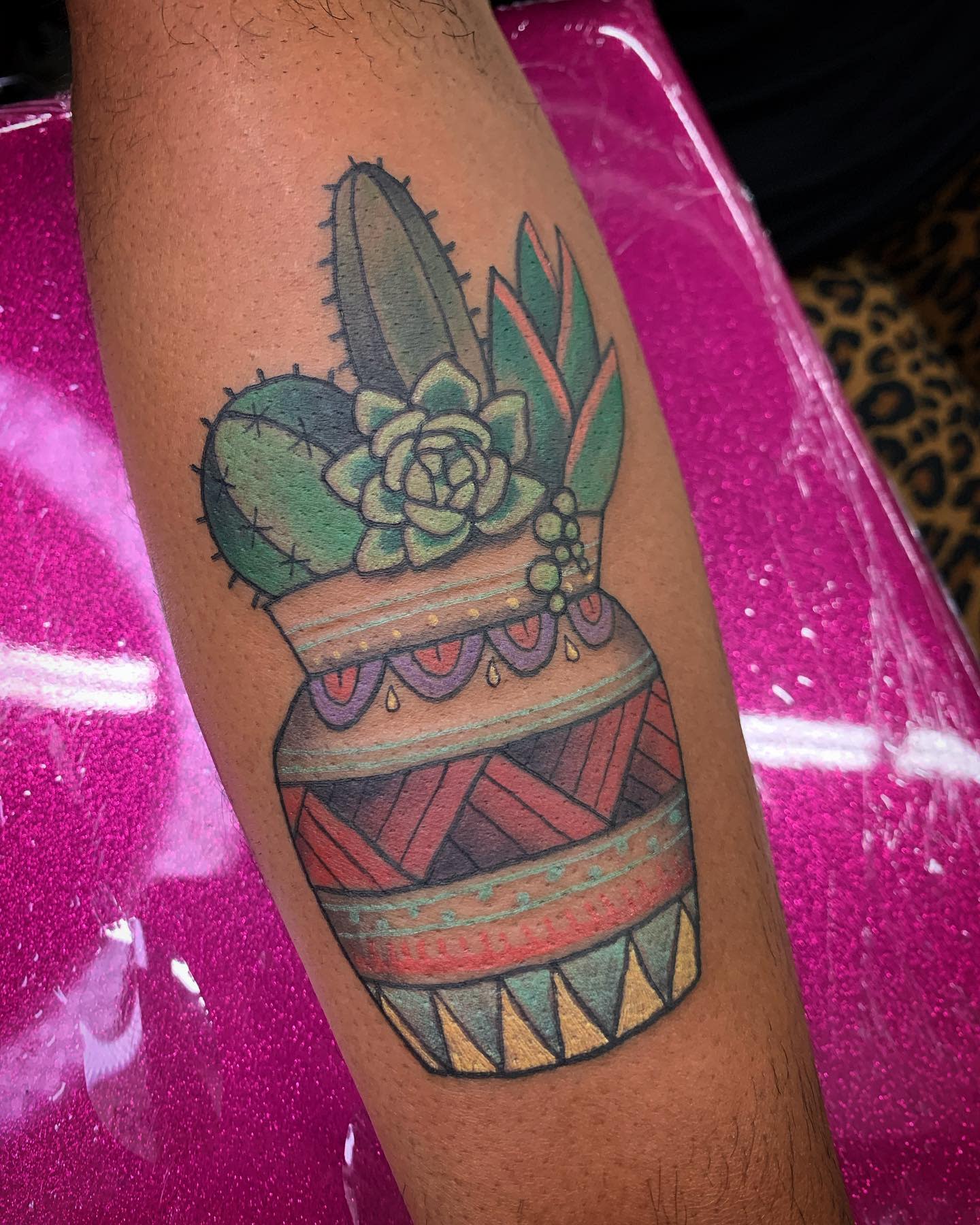 Colorful tattoo of cacti in a patterned pot on a forearm