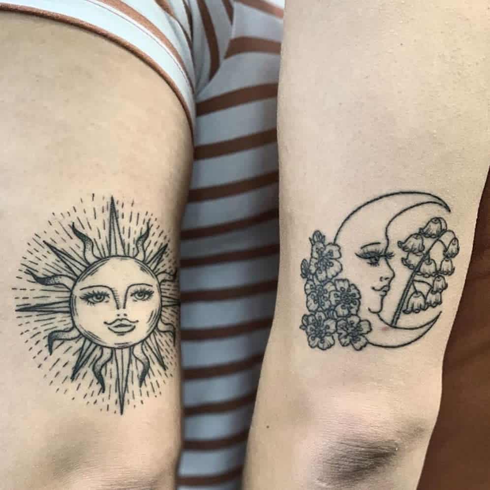 Sun face tattoo on one arm and moon face with flowers tattoo on the other arm