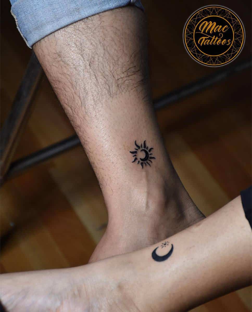 Two ankles with matching sun and moon tattoos