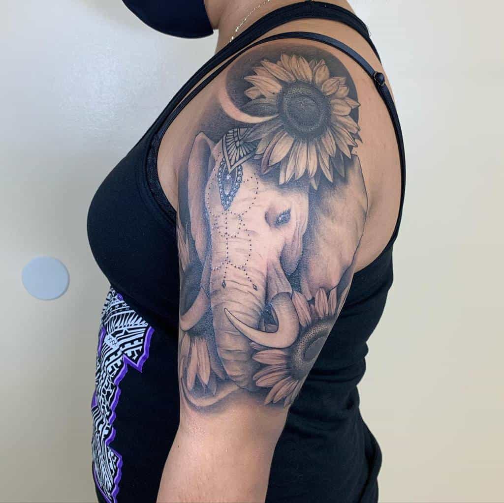 Tattoo of an elephant and sunflowers on a woman's upper arm