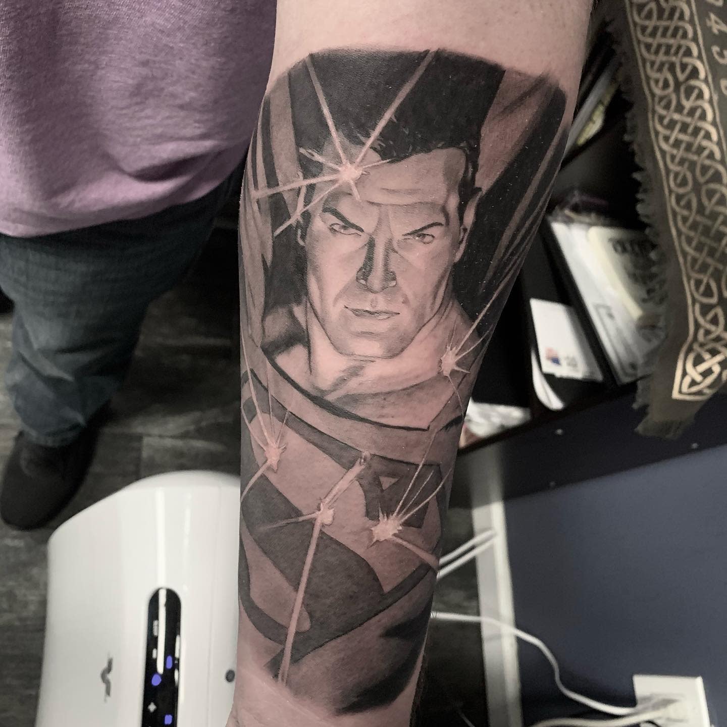 Forearm tattoo of Superman with beams of light and the Superman logo