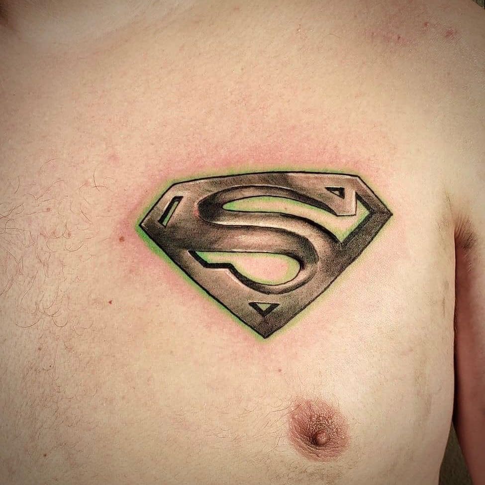 Chest tattoo of a shaded Superman logo on bare skin