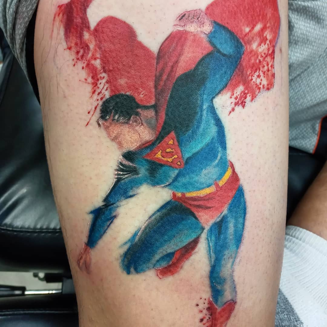 Tattoo of Superman breaking chains with red and blue ink on an arm