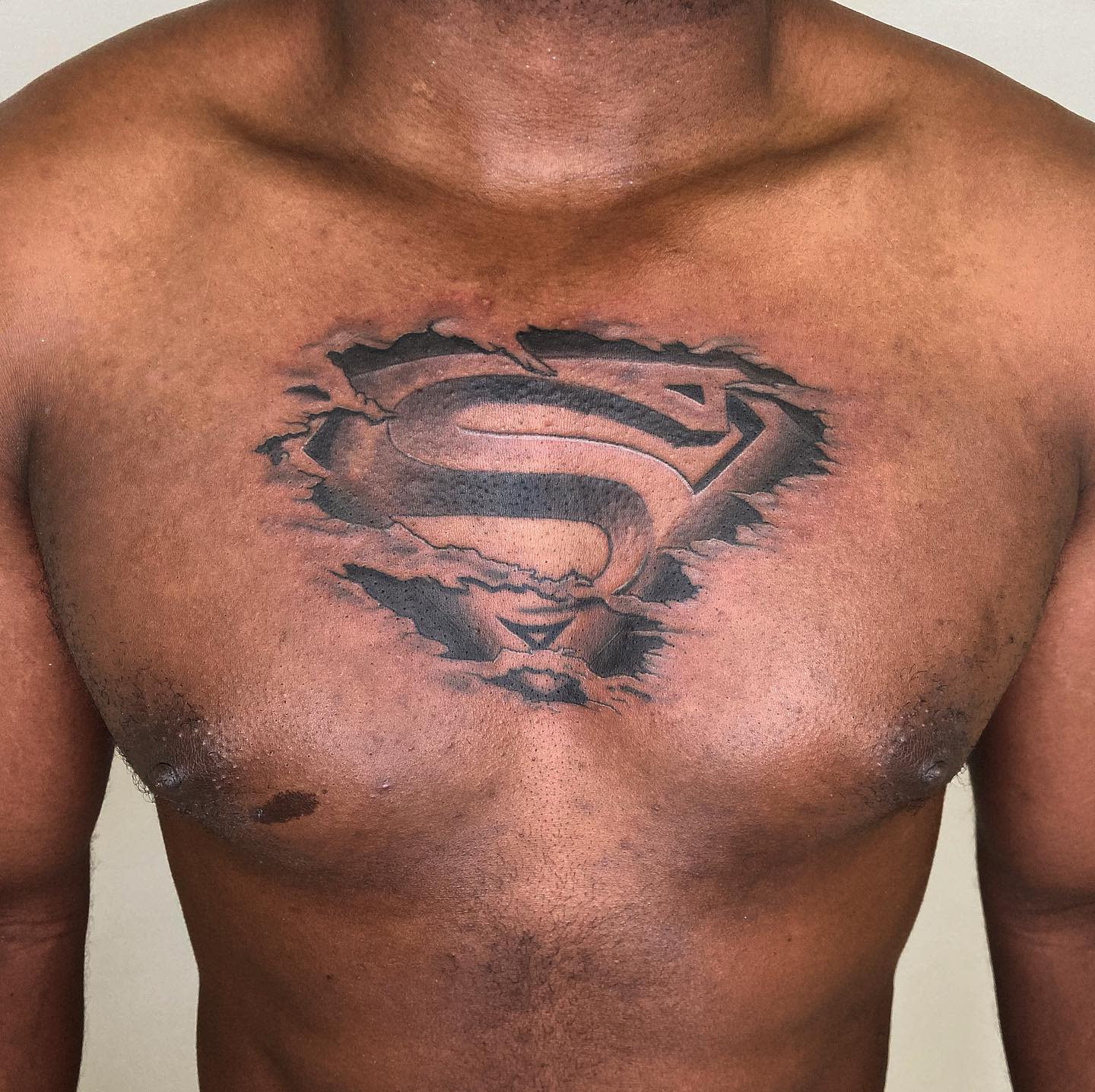 A chest tattoo of the Superman logo with a 3D torn skin effect