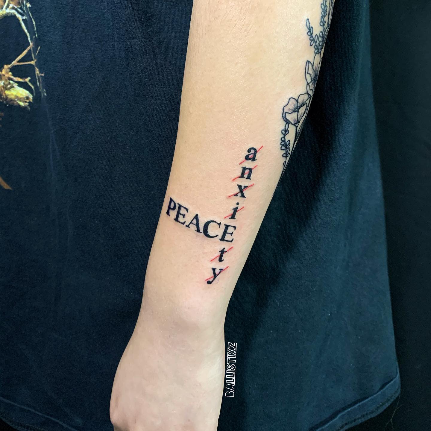 Forearm tattoo with "anxiety" crossed out and replaced with "PEACE" in bold