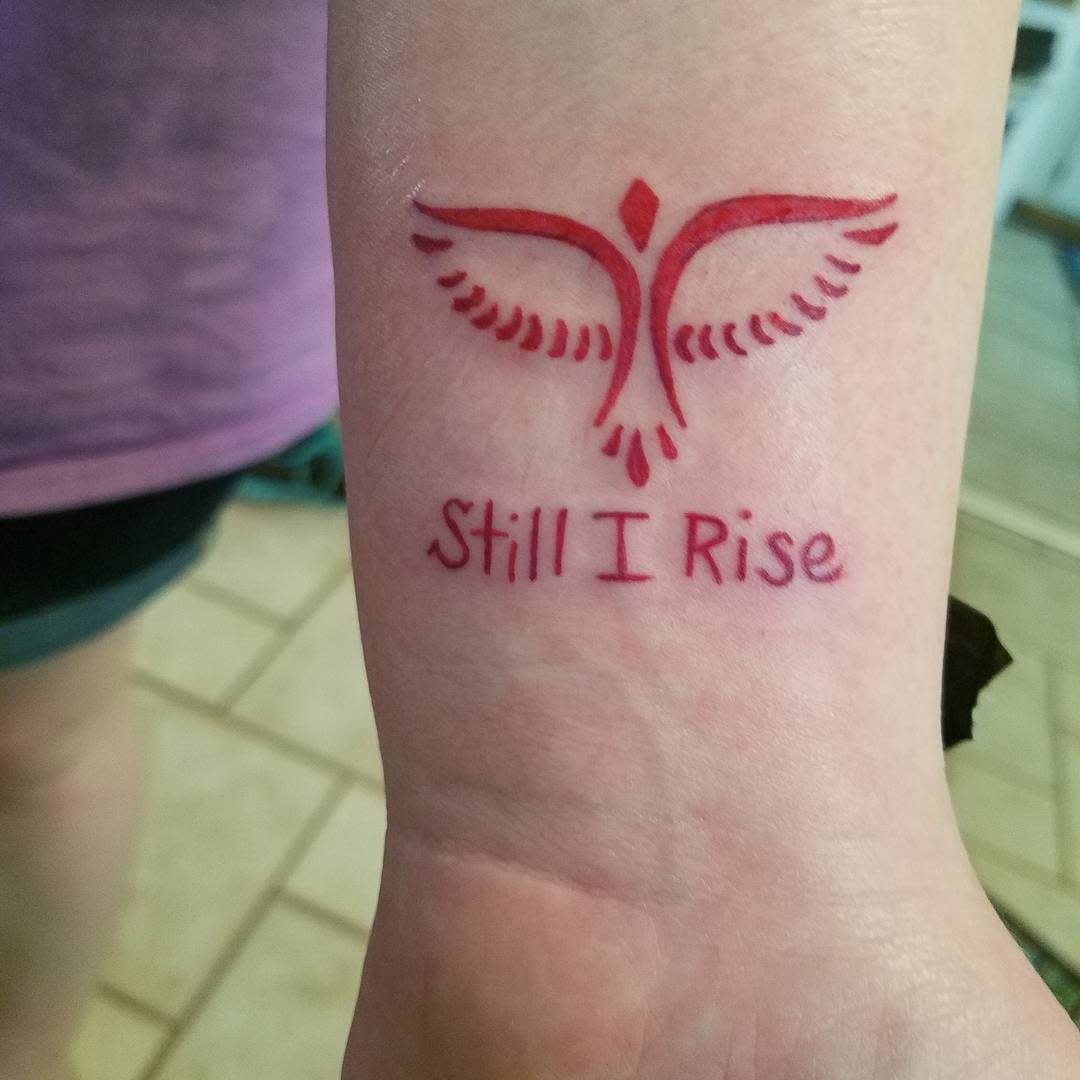 Wrist tattoo of a phoenix and the words "Still I Rise" underneath
