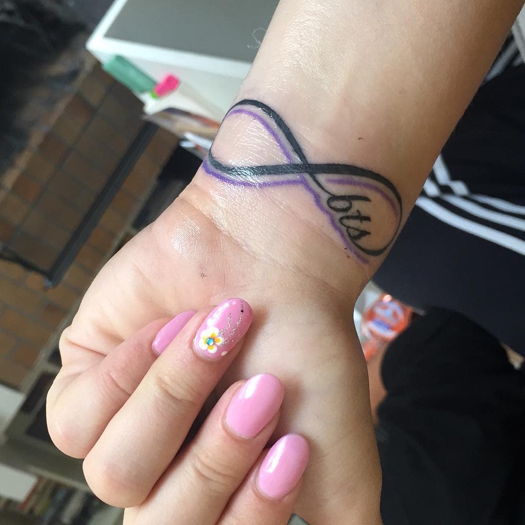 Wrist tattoo of a purple infinity symbol with "bts"