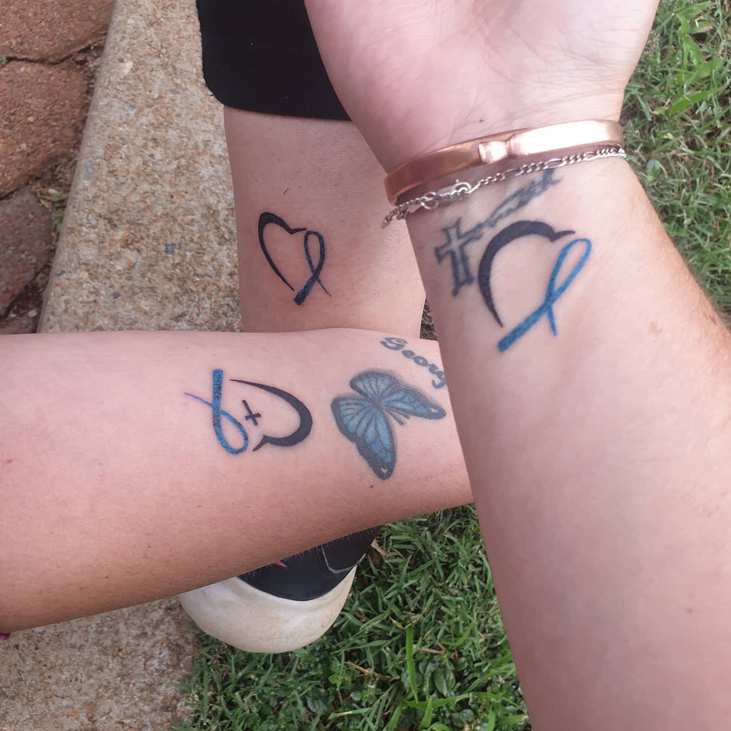 Three individuals display tattoos, two featuring a heart with a cross and ribbon, one with a butterfly
